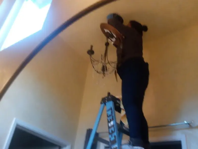 Electrician installing a chandelier in a Morrison residence